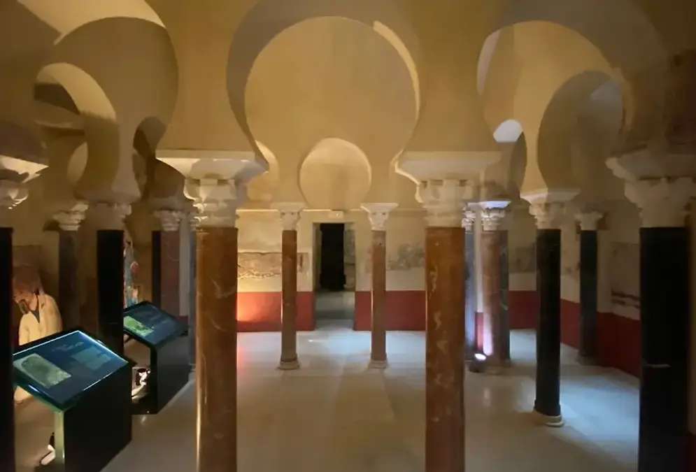 Vaulted interior of the Caliphal Baths in Córdoba showing star-shaped skylights and marble columns