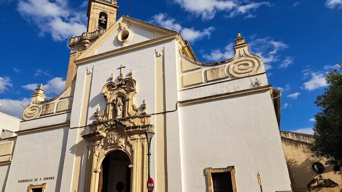 Baroque stone portal and slender brick bell tower of the Iglesia de San Andrés in Córdoba, seen from the Plaza de San Andrés in soft afternoon light