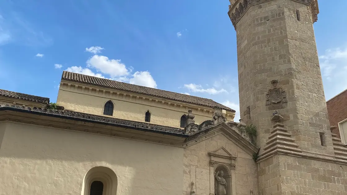 Ochre-limewashed Iglesia de San Nicolás de la Villa in Córdoba with its Mudéjar-based tower and glazed pyramidal roof rising above a narrow street
