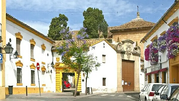 Whitewashed facade of the former Santa Isabel de los Ángeles convent on the Plaza del Conde de Priego in Córdoba, with a stone doorway and a pediment relief