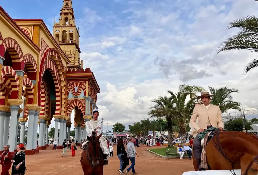 Feria de Córdoba fairgrounds with colorful casetas and horseback riders in festive atmosphere