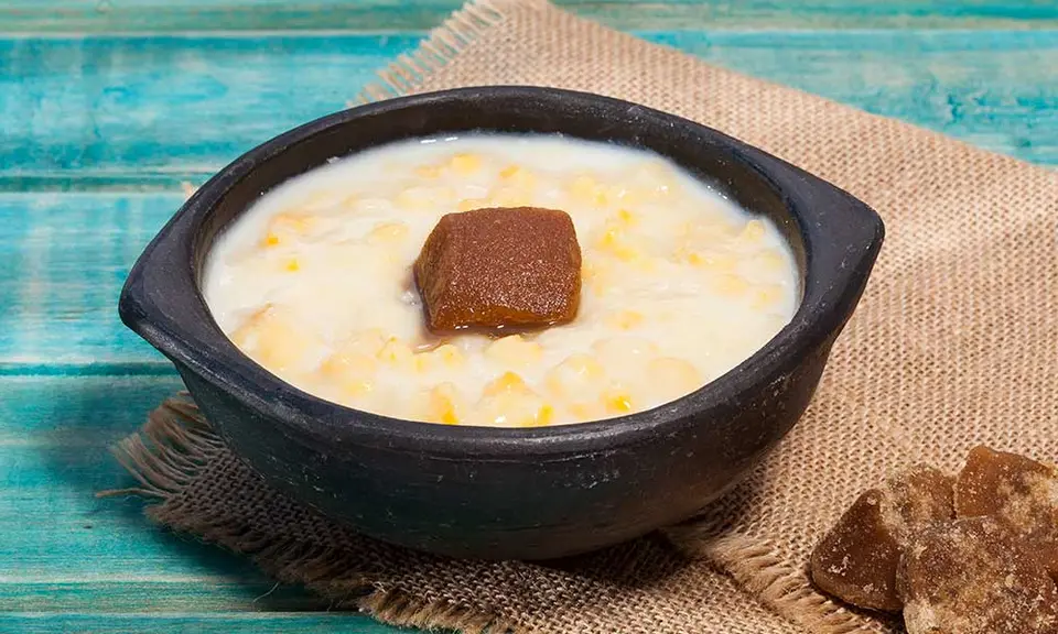 Bowl of pale mazamorra cordobesa garnished with black olives, grapes and boiled egg