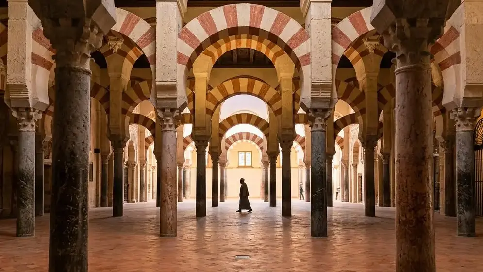 The Mezquita-Catedral tower and roofline at dawn, warm light on stone, Guadalquivir river visible below