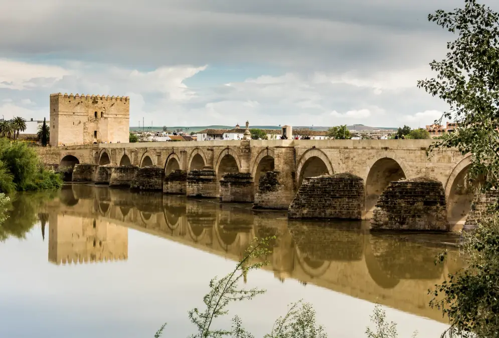 Roman Bridge of Córdoba illuminated at dusk with reflections on the Guadalquivir