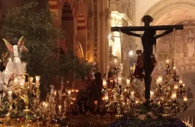 Nocturnal procession of hooded penitents in front of the illuminated Mezquita during Córdoba's Holy Week