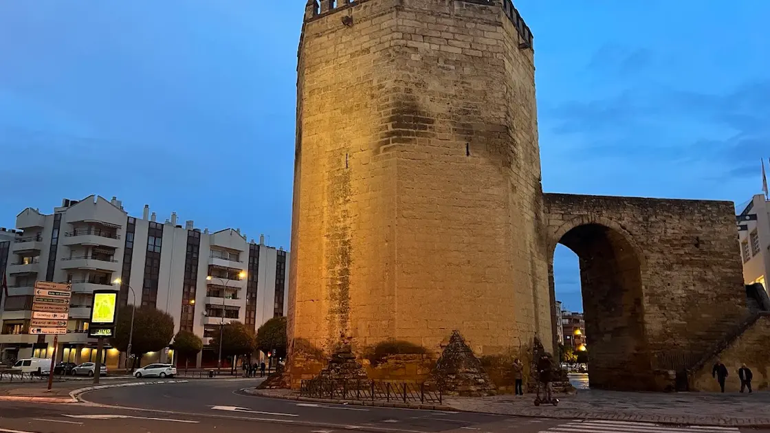 Octagonal Torre de la Malmuerta in Córdoba with crenellated top and the wall arch beside it on Avenida de Ollerías in warm afternoon light